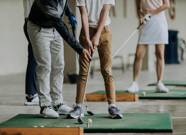 People practicing golf on a simulator indoors